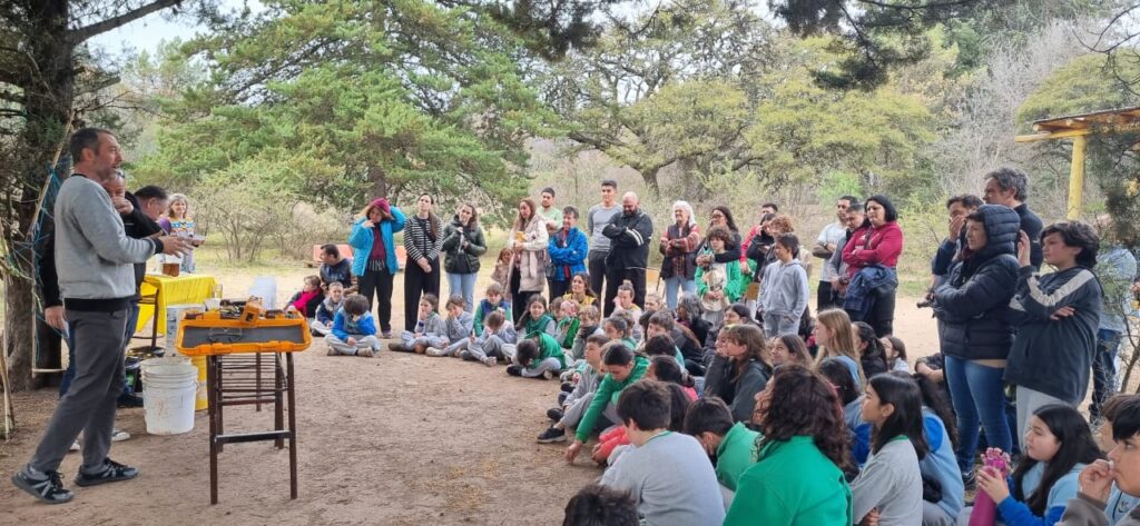 Alumnos, padres y maestros, reunidos en el patio de la escuela, escuchando a referentes ambientales hablar de compostaje